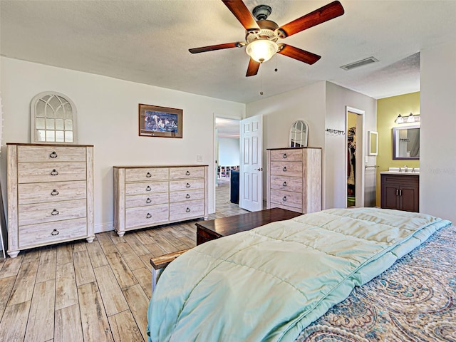 5832 Monroe Rd, Venice, FL 34293 - bedroom featuring light wood-type flooring, a spacious closet, a sink, a ceiling fan, and connected bathroom