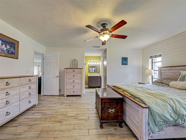 5832 Monroe Rd, Venice, FL 34293 - bedroom featuring multiple windows, light wood-style floors, a textured ceiling, wooden walls, and ensuite bathroom