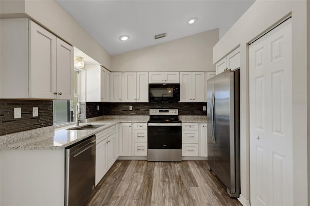 25509 Arequipa Dr, Punta Gorda, FL 33983 - kitchen featuring appliances with stainless steel finishes, a sink, vaulted ceiling, decorative backsplash, and white cabinets