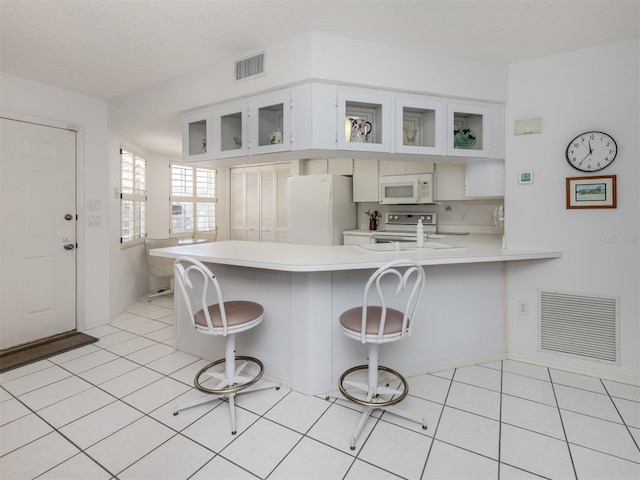 528 W Venice Ave Unit 1, Venice, FL 34285 - kitchen featuring white appliances, light countertops, a peninsula, a breakfast bar area, and light tile patterned flooring