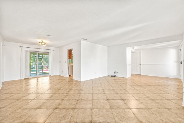 empty room featuring a textured ceiling and light tile patterned floors