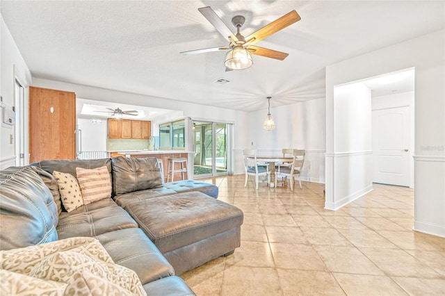 living area with a ceiling fan, light tile patterned floors, and baseboards