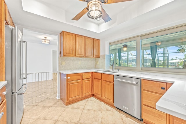 kitchen featuring appliances with stainless steel finishes, a sink, a ceiling fan, light tile patterned floors, and light stone counters