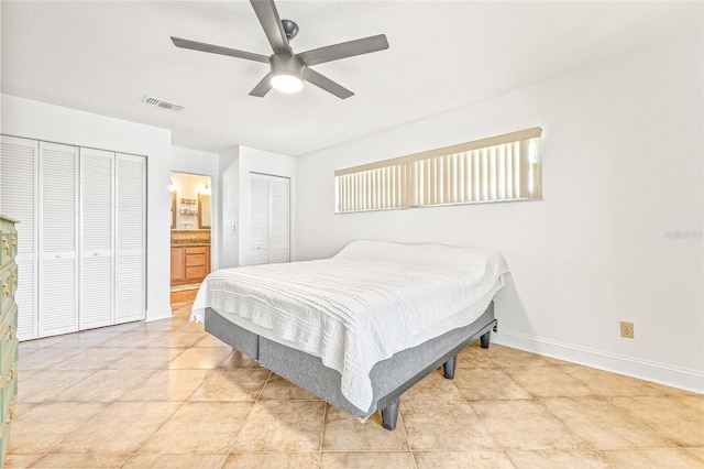 tiled bedroom with baseboards, ceiling fan, and ensuite bath