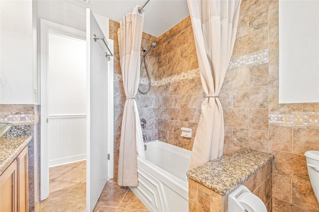 full bathroom featuring toilet, shower / bathtub combination with curtain, a wainscoted wall, tile patterned flooring, and vanity