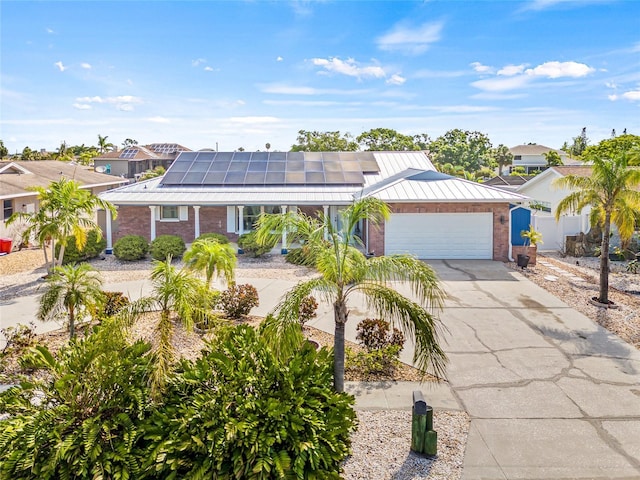 731 Flamingo Dr, Apollo Beach, FL 33572 - view of front of house featuring brick siding, a garage, a standing seam roof, a metal roof, and driveway