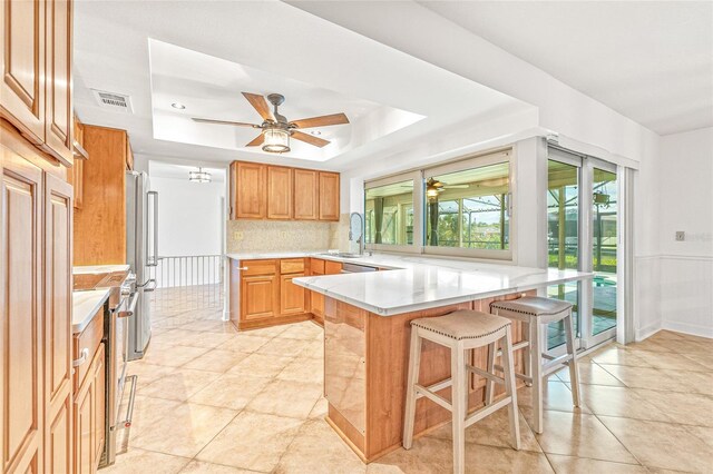 731 Flamingo Dr, Apollo Beach, FL 33572 - kitchen with a peninsula, ceiling fan, a kitchen breakfast bar, and a tray ceiling