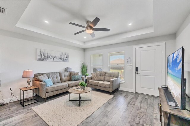 12031 Saragossa Ln, North Port, FL 34287 - living room featuring a raised ceiling, ceiling fan, light wood-type flooring, recessed lighting, and baseboards