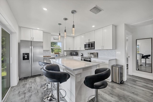 12031 Saragossa Ln, North Port, FL 34287 - kitchen featuring stainless steel appliances, light wood finished floors, a kitchen bar, white cabinetry, and recessed lighting