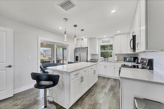 12031 Saragossa Ln, North Port, FL 34287 - kitchen with appliances with stainless steel finishes, a sink, tasteful backsplash, a kitchen breakfast bar, and wood finished floors