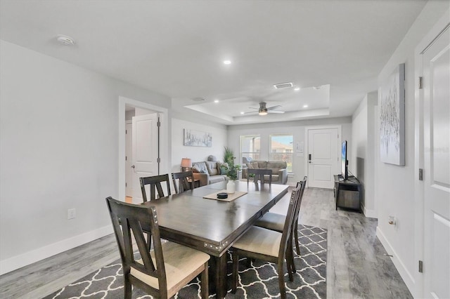 12031 Saragossa Ln, North Port, FL 34287 - dining room featuring light wood finished floors, a tray ceiling, a ceiling fan, baseboards, and recessed lighting