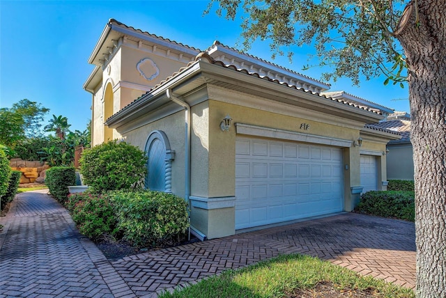 212 Triano Cir Unit 212, Venice, FL 34292 - view of property exterior featuring stucco siding, decorative driveway, a garage, and a tile roof