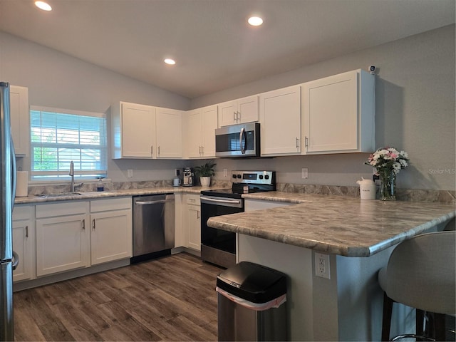 3003 58th Way E, Palmetto, FL 34221 - kitchen featuring appliances with stainless steel finishes, a sink, a peninsula, white cabinetry, and a breakfast bar