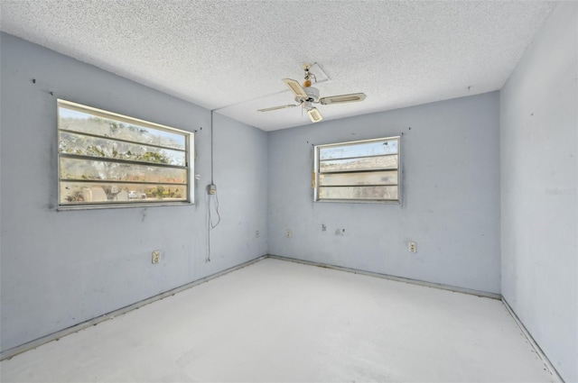 empty room with plenty of natural light, a ceiling fan, concrete floors, and a textured ceiling