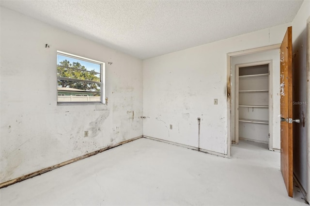 unfurnished bedroom with concrete flooring and a textured ceiling