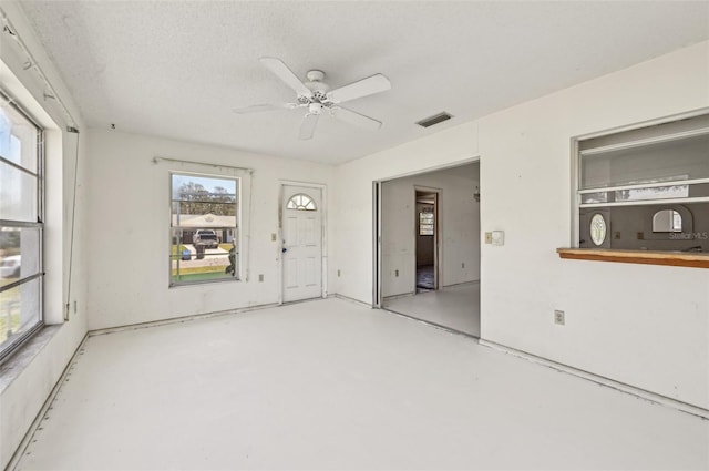 spare room featuring concrete floors, healthy amount of natural light, and ceiling fan