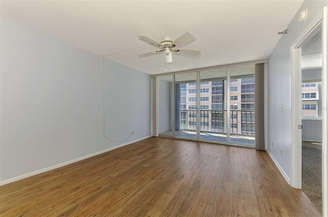 232 Saint Augustine Ave Unit 505, Venice, FL 34285 - spare room featuring hardwood / wood-style flooring, a ceiling fan, a wall of windows, and baseboards