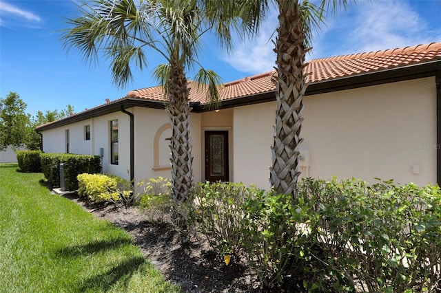 9823 Haze Dr, Venice, FL 34292 - view of property exterior featuring a tiled roof, stucco siding, and a lawn