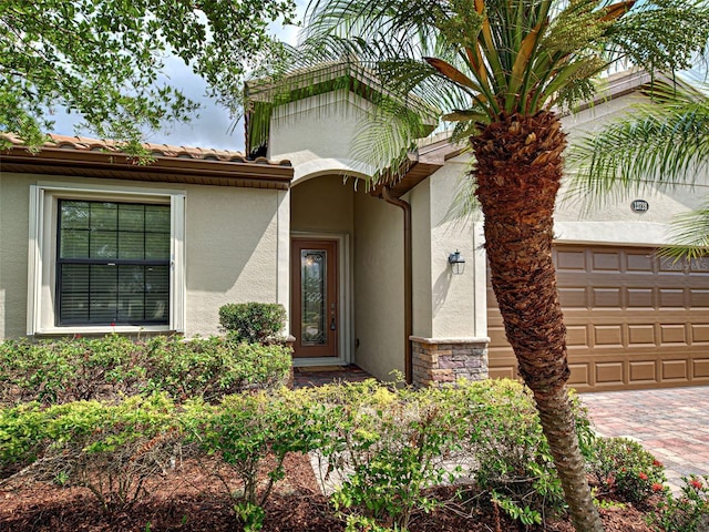 property entrance featuring stucco siding, decorative driveway, and stone siding