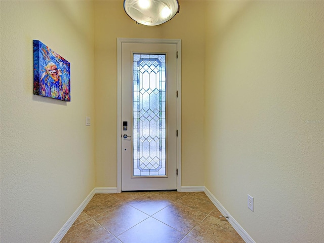entryway with light tile patterned floors, baseboards, and a textured wall