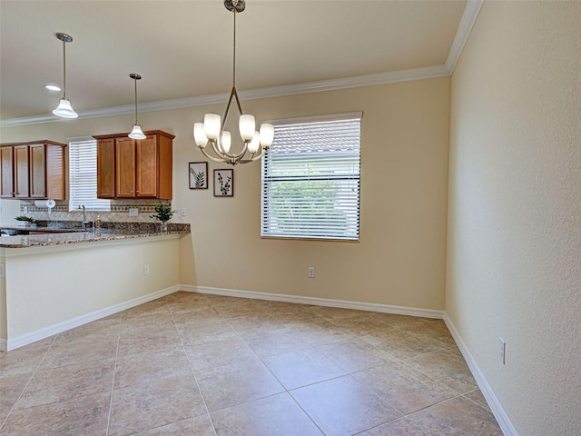 kitchen with brown cabinets, stone counters, ornamental molding, a chandelier, and light tile patterned floors