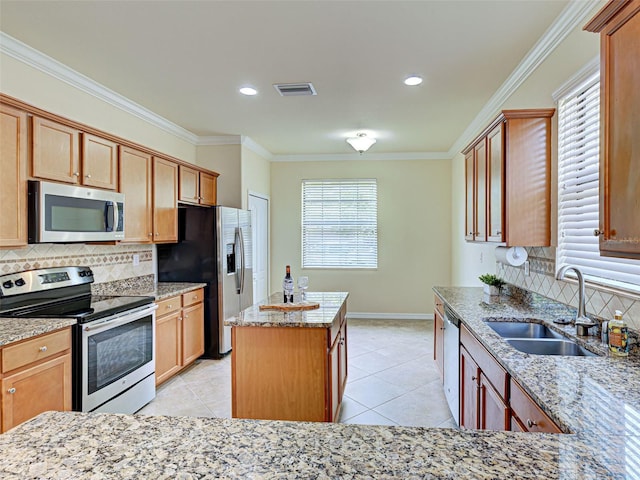 kitchen with appliances with stainless steel finishes, a sink, backsplash, a center island, and ornamental molding