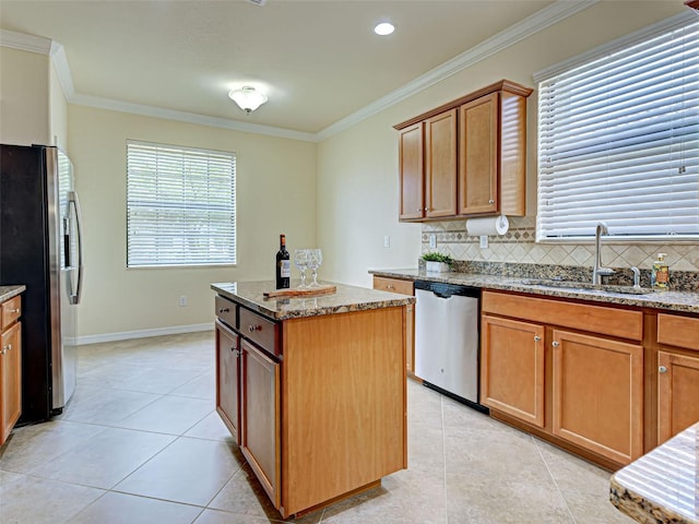 kitchen featuring appliances with stainless steel finishes, a sink, light tile patterned floors, ornamental molding, and dark stone counters