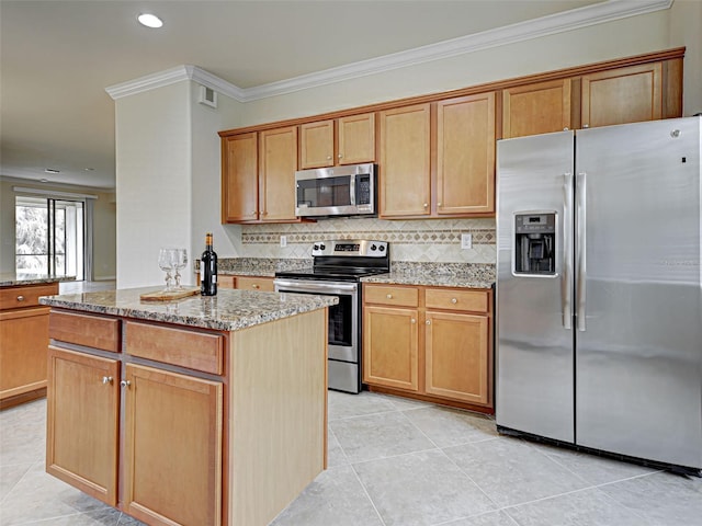 kitchen with stainless steel appliances, light stone counters, ornamental molding, a center island, and light tile patterned floors