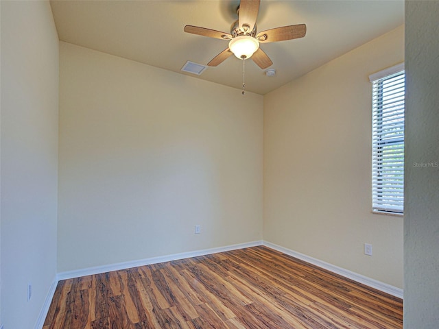empty room featuring wood finished floors, a ceiling fan, baseboards, and a smoke detector