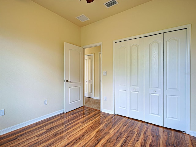 unfurnished bedroom featuring dark wood-type flooring, baseboards, a closet, and ceiling fan