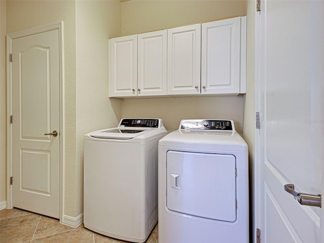 laundry area with washer and dryer, cabinet space, baseboards, and light tile patterned flooring