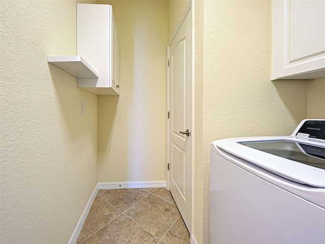 clothes washing area featuring washer / dryer, cabinet space, a textured wall, baseboards, and light tile patterned floors