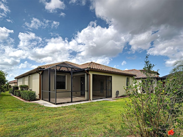 back of house featuring a tile roof, stucco siding, and a yard