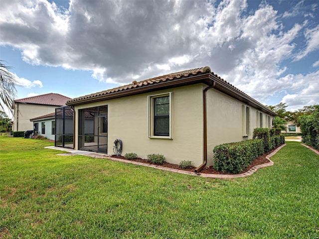 back of property with a yard, stucco siding, and a tiled roof