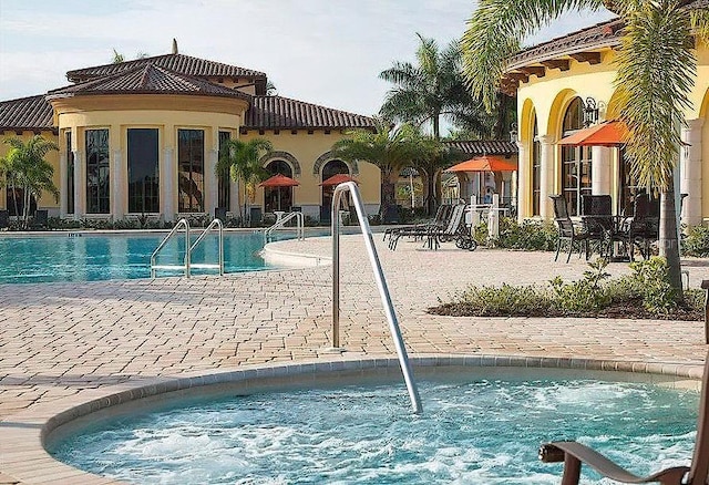 community pool with a hot tub and a patio area