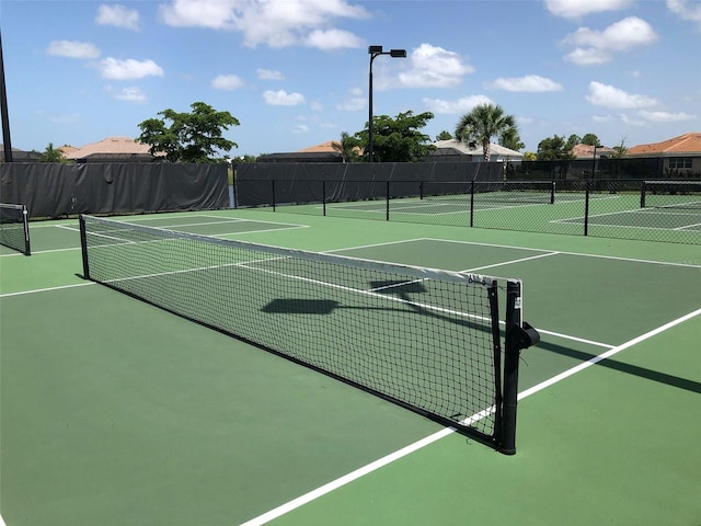 view of tennis court with community basketball court and fence
