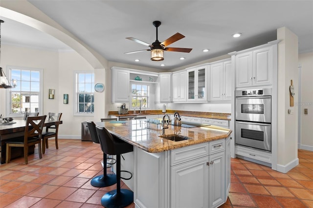63 Palm Dr, Placida, FL 33946 - kitchen featuring stainless steel double oven, arched walkways, baseboards, white cabinets, and ceiling fan