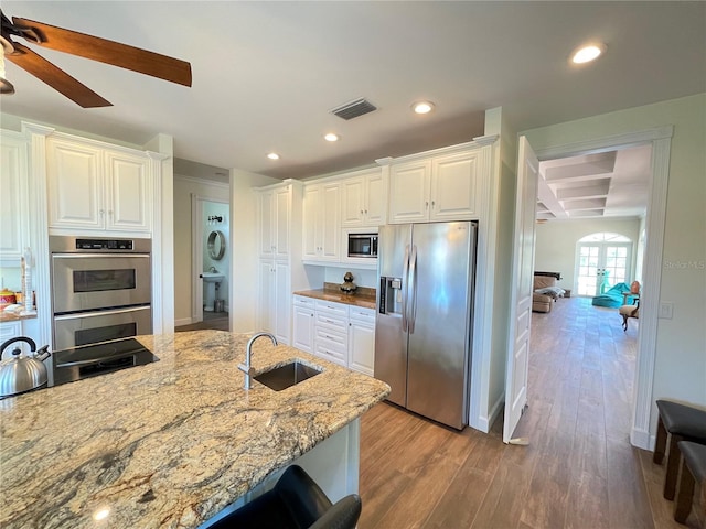 63 Palm Dr, Placida, FL 33946 - kitchen featuring appliances with stainless steel finishes, a sink, wood finished floors, light stone countertops, and white cabinetry