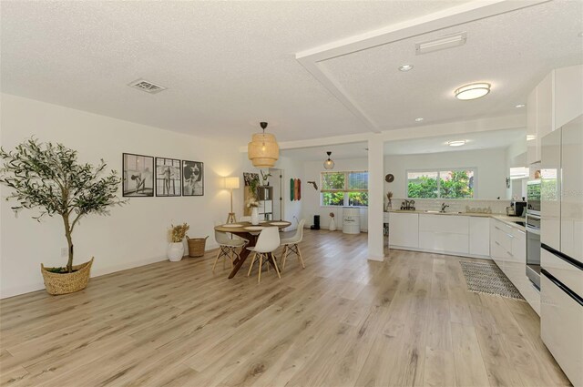 4321 Shamrock Dr, Venice, FL 34293 - kitchen with white cabinets, modern cabinets, light countertops, light wood-style flooring, and a textured ceiling