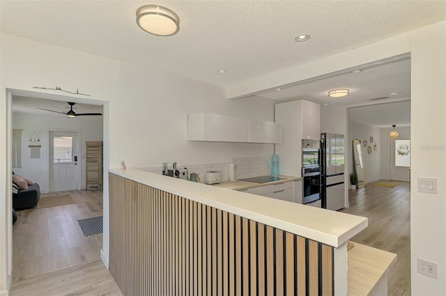 4321 Shamrock Dr, Venice, FL 34293 - kitchen with black electric stovetop, light wood-style floors, stainless steel double oven, decorative backsplash, and light countertops
