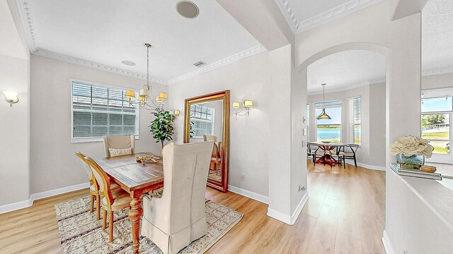 632 Tanana Fall Dr, Ruskin, FL 33570 - dining space with arched walkways, ornamental molding, light wood-type flooring, baseboards, and a chandelier
