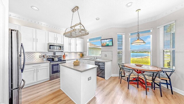 632 Tanana Fall Dr, Ruskin, FL 33570 - kitchen featuring stainless steel appliances, ornamental molding, light wood finished floors, white cabinets, and tasteful backsplash