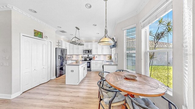 632 Tanana Fall Dr, Ruskin, FL 33570 - kitchen with ornamental molding, stainless steel appliances, a kitchen island, white cabinetry, and backsplash