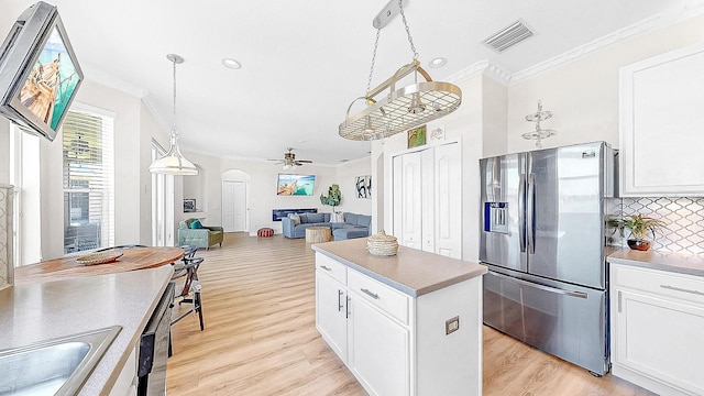 632 Tanana Fall Dr, Ruskin, FL 33570 - kitchen with stainless steel fridge, ornamental molding, arched walkways, light wood-style floors, and backsplash