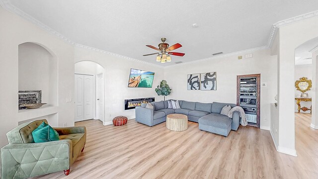 632 Tanana Fall Dr, Ruskin, FL 33570 - living room featuring arched walkways, ceiling fan, baseboards, ornamental molding, and light wood-style floors