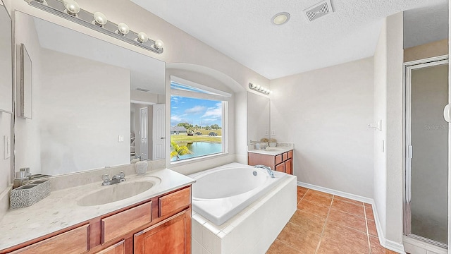 632 Tanana Fall Dr, Ruskin, FL 33570 - full bath featuring a shower stall, a bath, two vanities, tile patterned flooring, and a textured ceiling