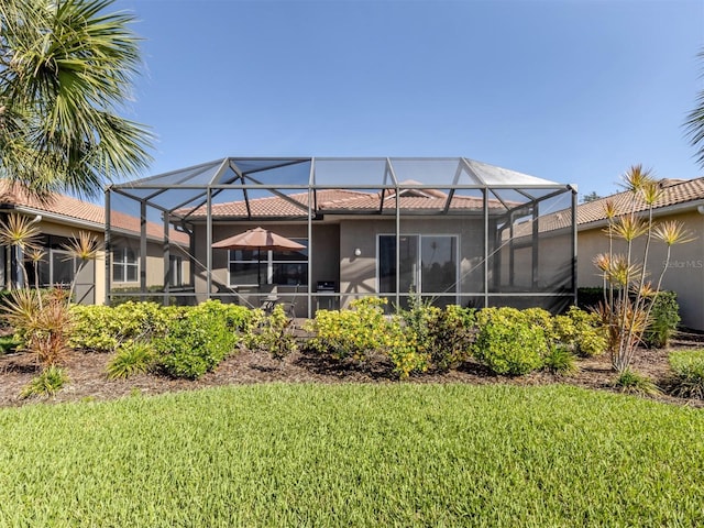 165 Tiziano Way N, Venice, FL 34275 - rear view of property with stucco siding, glass enclosure, and a lawn