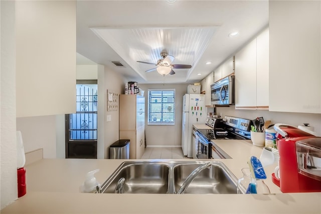 410 Mission Trl E Unit B, Venice, FL 34285 - kitchen with stainless steel appliances, a sink, a tray ceiling, white cabinets, and light countertops