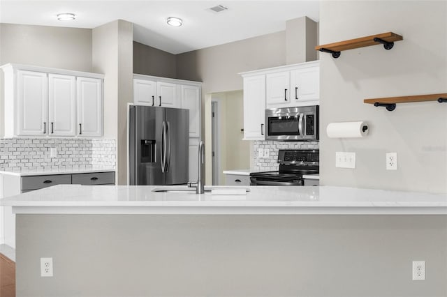 4305 Heyward St, North Port, FL 34291 - kitchen featuring stainless steel appliances, a sink, decorative backsplash, white cabinets, and a peninsula