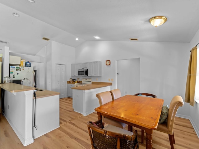 6199 Stamp St, Port Charlotte, FL 33981 - kitchen featuring white appliances, lofted ceiling, a peninsula, light wood-style floors, and a sink